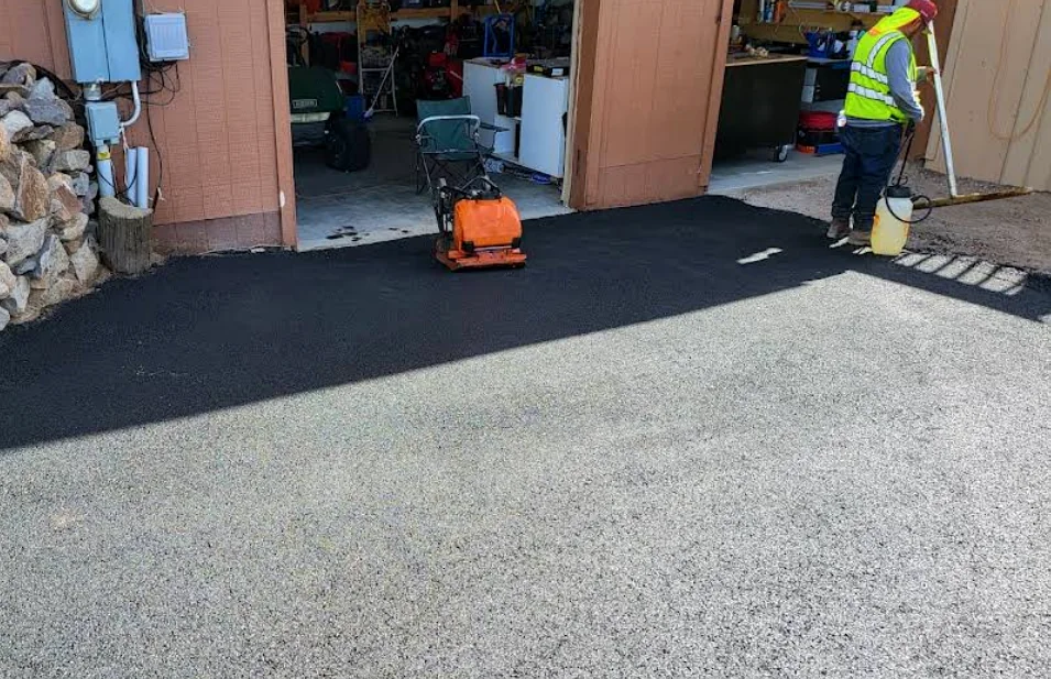 Fresh asphalt patch being compacted at a garage entrance
